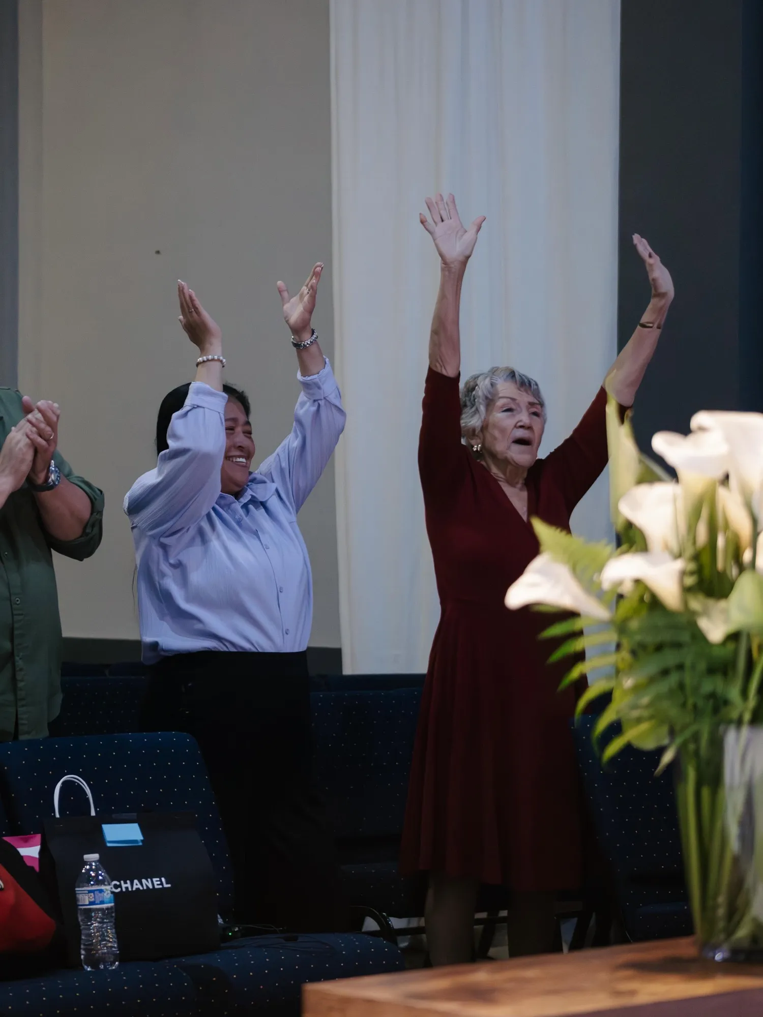 Two women worshipping with hands raised